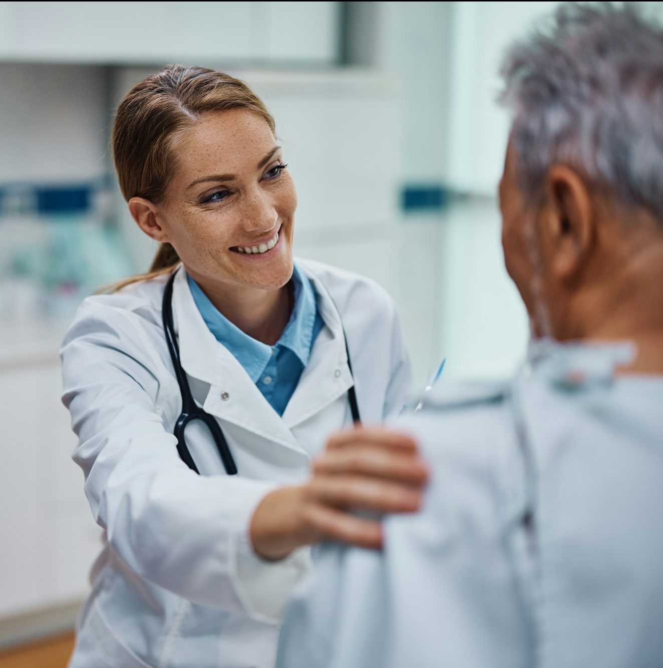 Happy doctor talking to her mature patient during medical exam at the clinic.